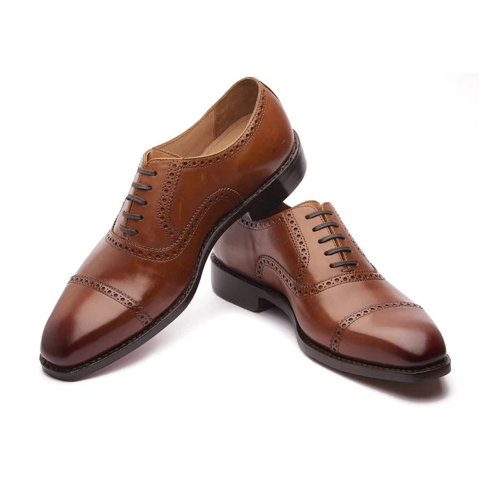 Close-up of brogue detailing on burgundy Oxford shoes