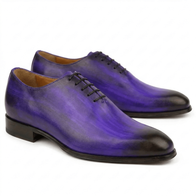 A pair of premium purple leather wholecut Oxford shoes featuring a vibrant hand-painted patina with dark burnished accents on the toe and heel, finished with elegant black lacing.