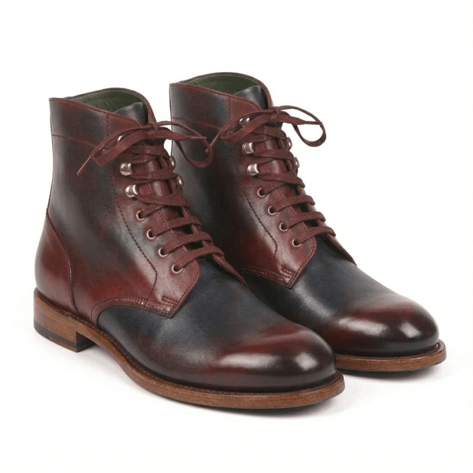 A pair of premium handcrafted leather lace-up boots featuring a sophisticated two-tone patina in burgundy and dark navy, with silver-toned speed hooks and a durable Goodyear-welted leather sole.