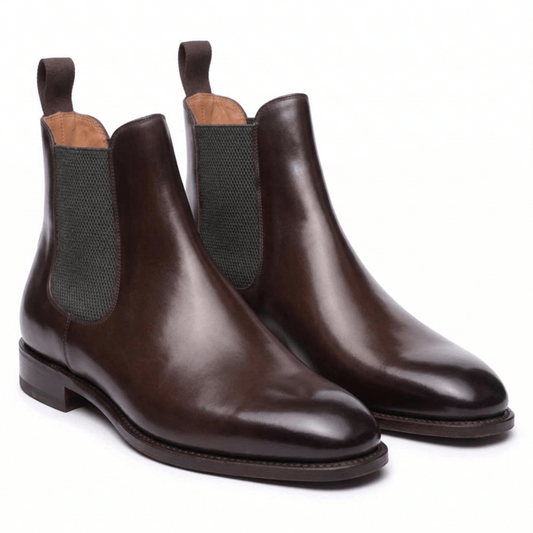 Elegant dark brown leather Chelsea boots for men with a polished finish and olive green elastic side panels, perfect for styling with black jeans.