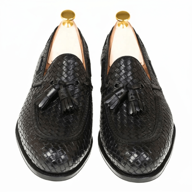 Top angle view of premium black woven leather loafers with elegant tassel detailing