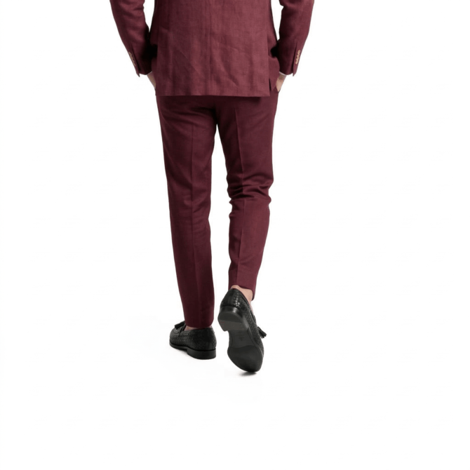 Side walking shot of men’s black leather tassel loafers paired with burgundy trousers