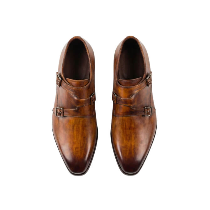 Top-down view of men's classic tan leather double monk strap shoes with silver buckles on a clean white background.