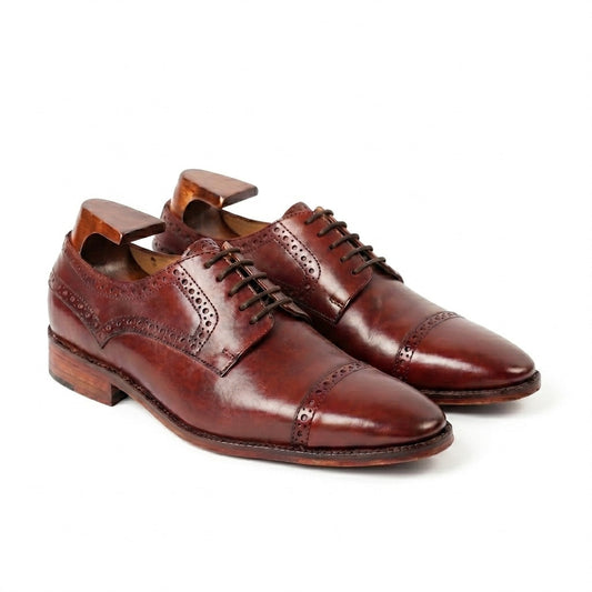 A pair of premium brown leather semi-brogue derby shoes featuring intricate perforated detailing, displayed with wooden shoe trees on a white background.