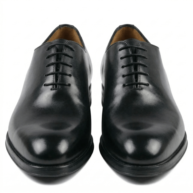 Front view of premium black leather wholecut Oxford shoes for men, featuring a minimalist lace-up design and polished finish on a clean white background.