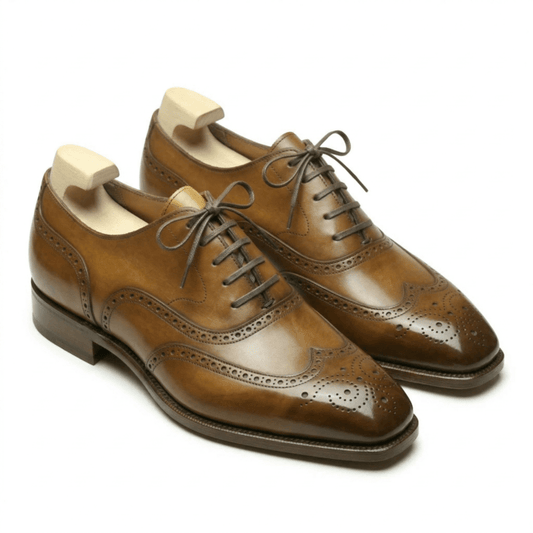 Three-quarter view of premium tan leather wingtip brogue oxford shoes for men featuring a hand-finished patina, intricate medallion toe, and wooden shoe trees.