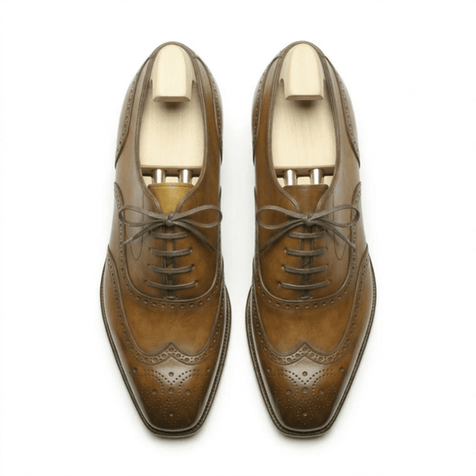 Top-down view of premium tan leather wingtip brogue shoes for men with intricate perforated detailing and wooden shoe trees.