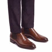 Model wearing brown leather Chelsea boots with dark trousers.
