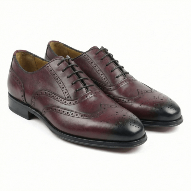 A pair of premium burgundy leather full brogue Oxford shoes featuring a traditional wingtip design with intricate decorative perforations and a dark burnished finish on the toe and heel.