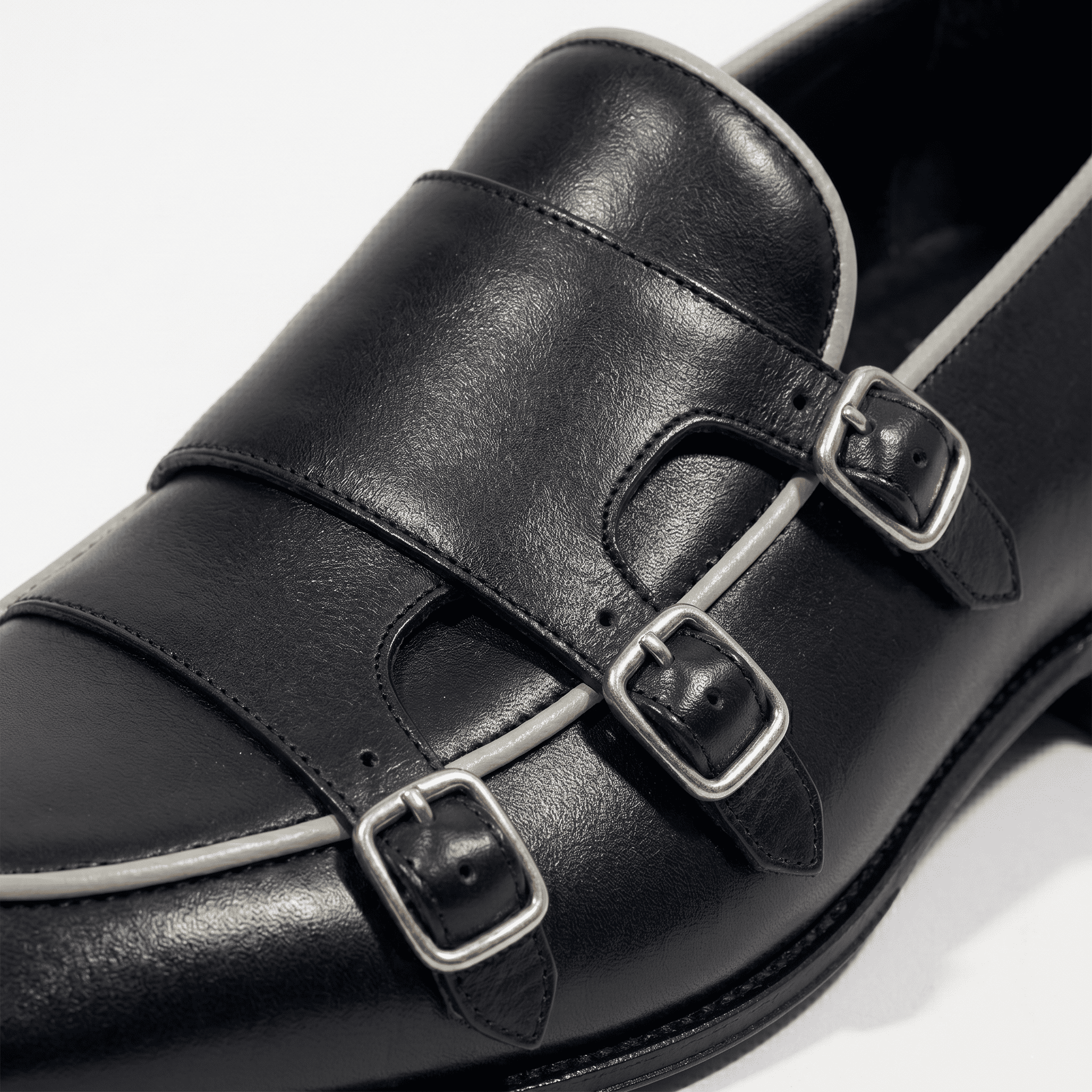 Close-up buckle detail of black triple monk strap leather shoes