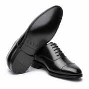 Black leather Oxford shoes arranged in a crossed position showing the polished upper