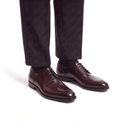 Man wearing dark brown leather Oxford shoes with formal trousers