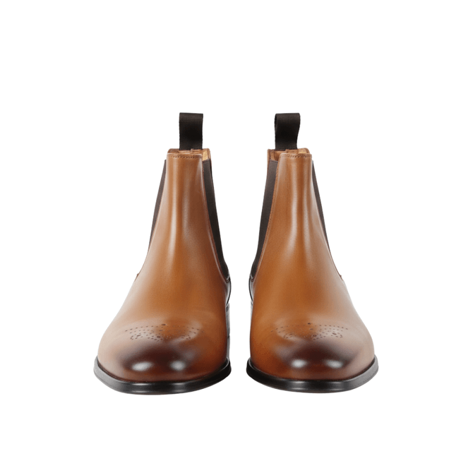 Front view of premium tan leather Chelsea boots featuring detailed brogue medallion toes and dark brown elastic side panels.