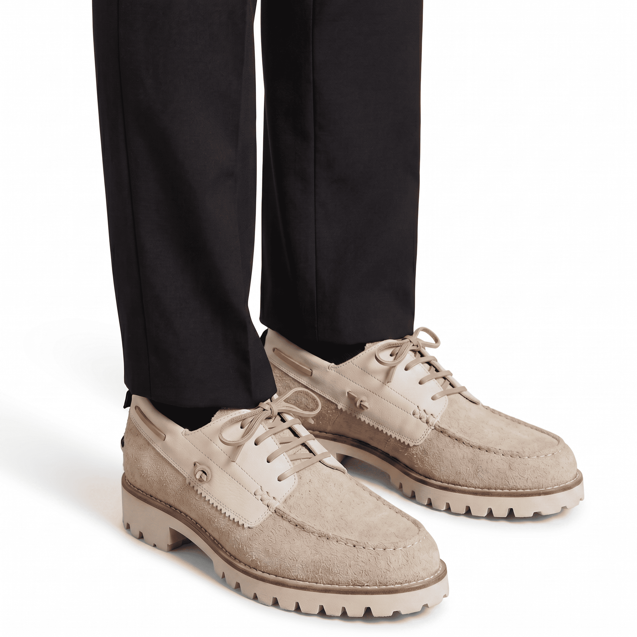 Lifestyle shot of the beige suede lug-sole shoes worn with black tailored trousers for a smart-casual contrast.