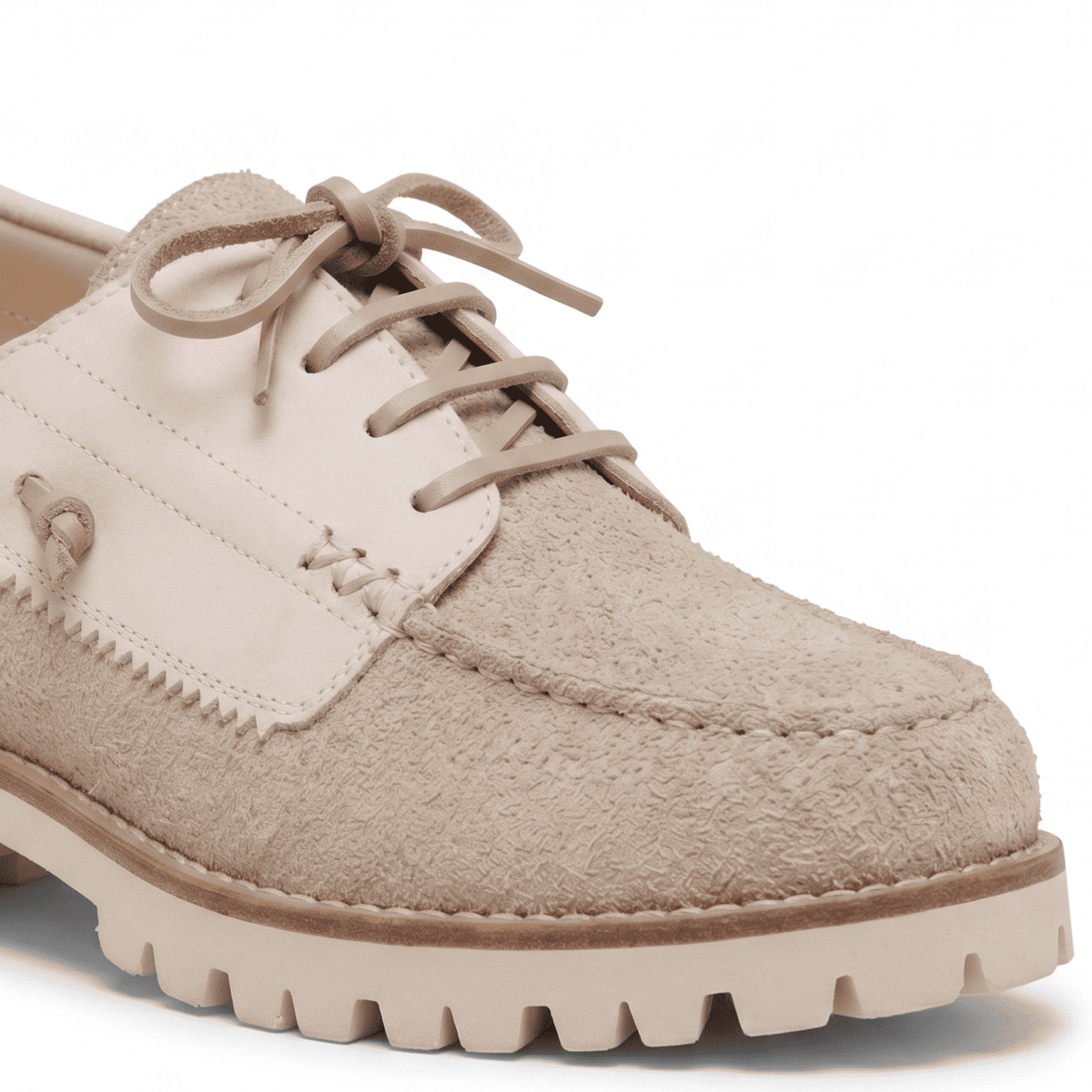 Macro close-up focusing on the contrast between the textured beige suede, smooth cream leather, and thick lacing.