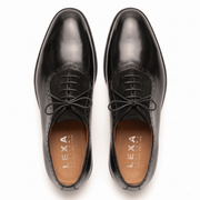 Overhead view of black formal Oxfords showing the almond toe shape, waxed laces, and tan leather interior lining.