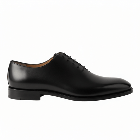 Side profile of a sleek black wholecut Oxford shoe showing the low-profile heel and calfskin texture.