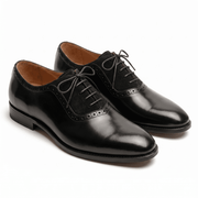 A pair of luxury black leather Oxford shoes featuring a unique suede mid-panel and classic brogue detailing.