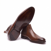 Angled bottom view of premium brown leather Chelsea boots for men displaying the durable sole and elegant profile.