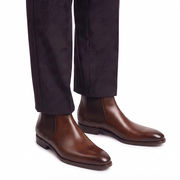 Men's brown leather Chelsea boots paired with formal trousers for a sophisticated smart-casual look.