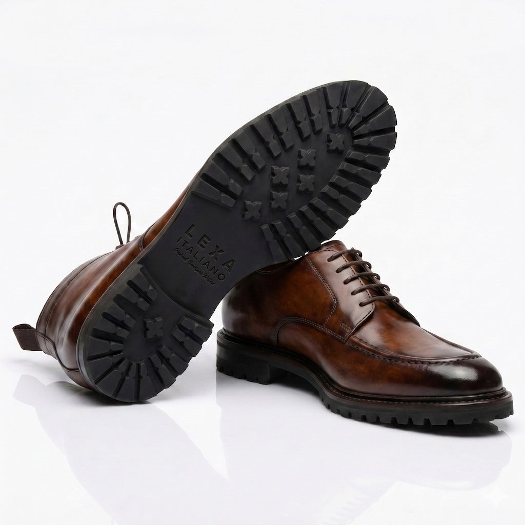 Men’s brown leather derby shoes with rugged lug sole and polished handcrafted finish on white background