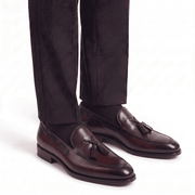 Man wearing burgundy leather tassel loafers with dark trousers