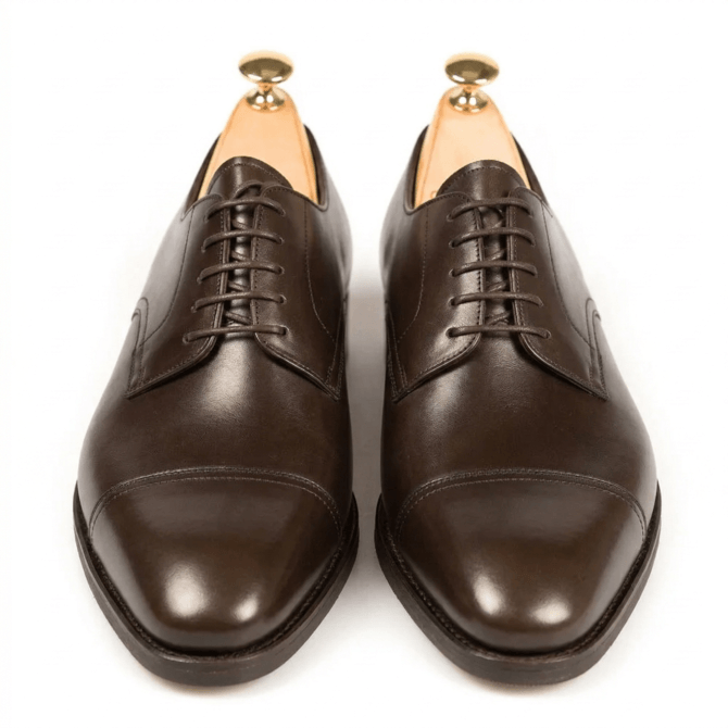 Pair of dark brown cap toe Oxford shoes with polished leather finish