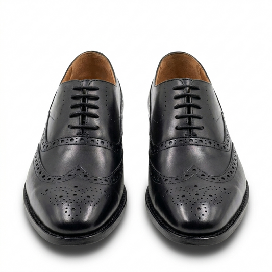 Front view of handcrafted black leather wingtip brogue Oxford shoes for men, showcasing intricate perforation details and a polished finish on a white background.