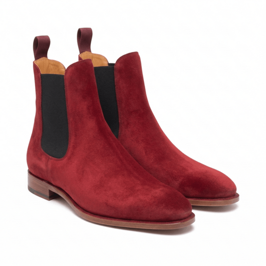 A pair of premium men's Chelsea boots in deep burgundy suede featuring black elastic side gussets, dual pull tabs, and a sleek almond-toe silhouette on a stacked leather sole.