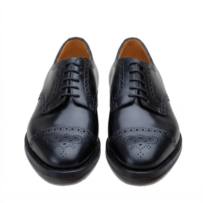 Pair of men's classic black leather brogue oxford shoes, front perspective, featuring traditional decorative punching and tan interior lining.
