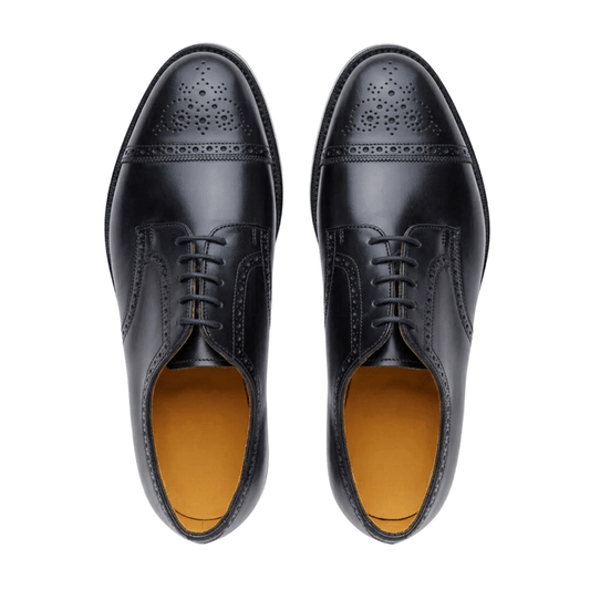 Top-down view of men's classic black leather oxford shoes with wingtip broguing, set against a clean white background.
