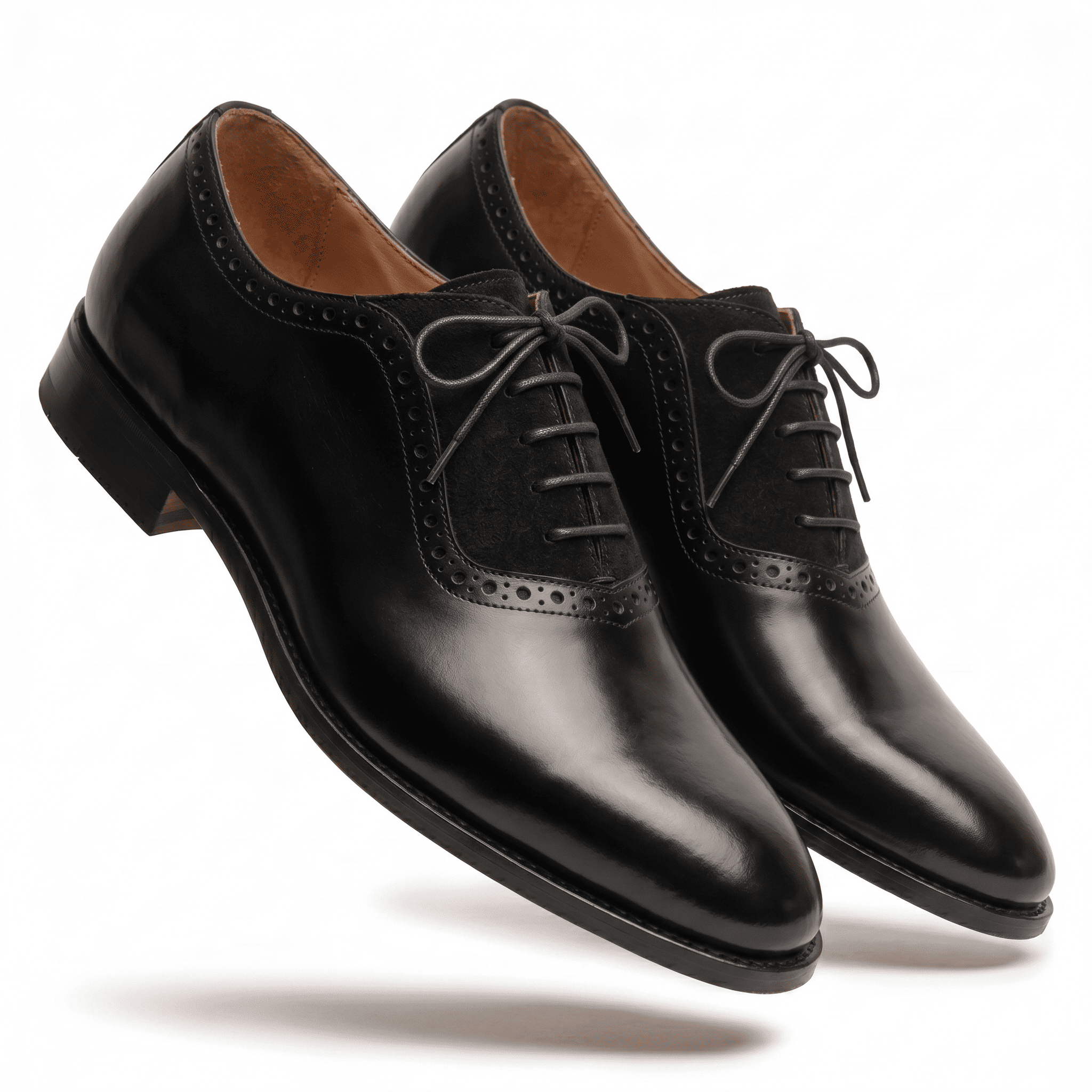 A dynamic, floating angled shot of the black leather and suede dress shoes against a white background.
