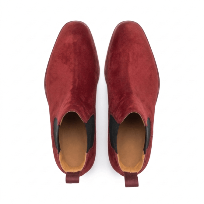 Top-down view of luxury men’s burgundy suede boots with black elastic side panels on a crisp white background.