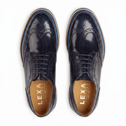 Birds-eye view of navy leather brogues showing the symmetrical wingtip design and gold-branded tan leather insoles.