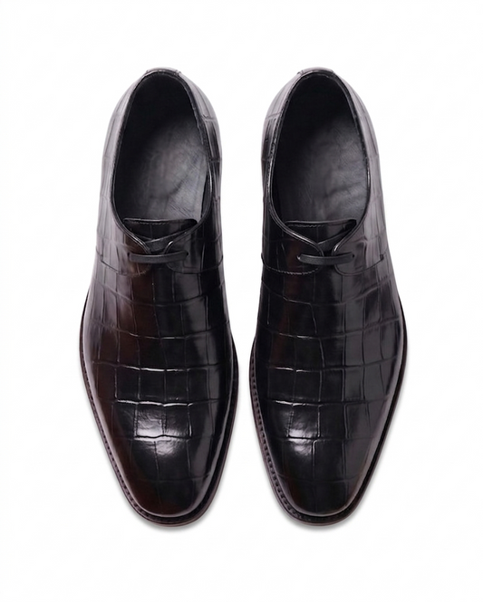 Top-down bird's-eye view of a pair of black crocodile-patterned leather dress shoes showing the symmetry and laces.