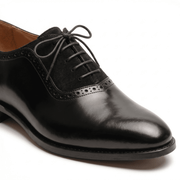Detailed close-up shot focusing on the contrast between the smooth black calfskin and the textured suede vamp.