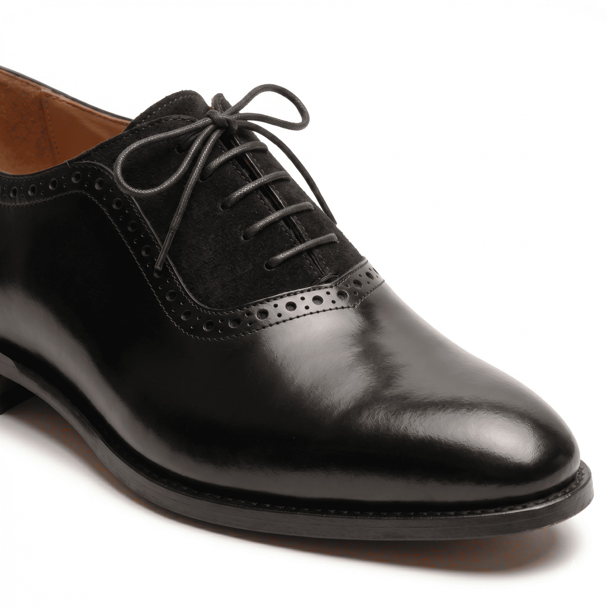 Detailed close-up shot focusing on the contrast between the smooth black calfskin and the textured suede vamp.