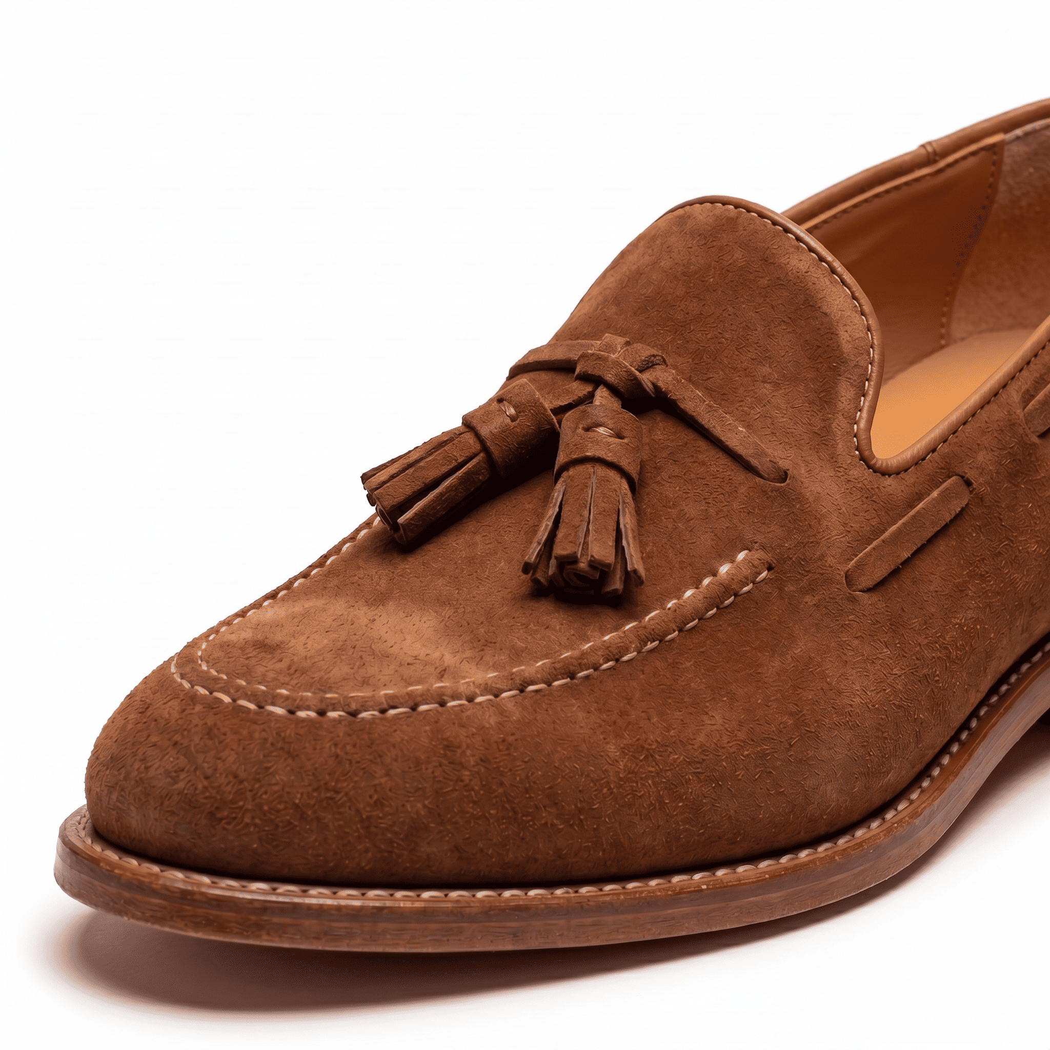 Close-up detail of tan suede tassel loafers stitching and tassels